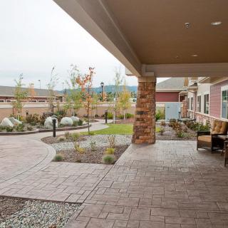 A covered patio with seating overlooks a landscaped garden and walkway.