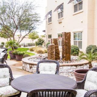 A patio area with outdoor furniture and landscaping in front of a building.