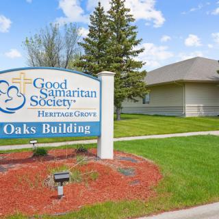A view of the Good Samaritan Society's Oaks Building with a nearby lawn and trees.