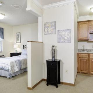 A cozy studio apartment featuring a comfortable bedroom area and a compact kitchen.