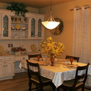 A cozy dining room with a table set for four, featuring decorative flowers and a warm ambiance.
