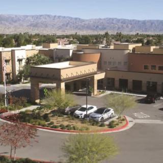 A hotel surrounded by desert landscaping and mountains in the background.