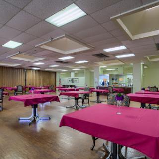 A spacious dining area featuring tables dressed with pink tablecloths, ready for guests.