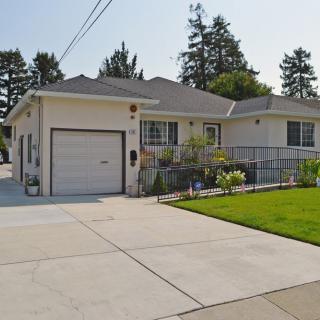 A suburban house with a driveway and garage, surrounded by a well-maintained lawn and trees.