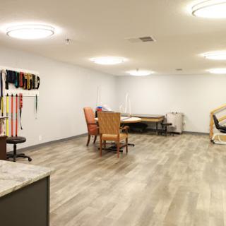 A spacious rehabilitation room featuring various furniture and exercise equipment.