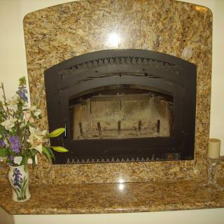 A decorated granite fireplace with a vase of flowers on the side.