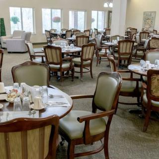 An empty dining room with neatly arranged tables and chairs, set for guests.
