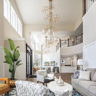 A spacious and modern living room with elegant chandeliers and abundant natural light.