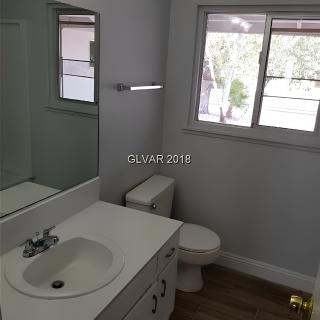 A clean and simple bathroom with a sink, toilet, and window.