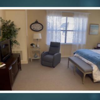A cozy bedroom featuring a comfortable chair, television, and a bed with blue bedding.