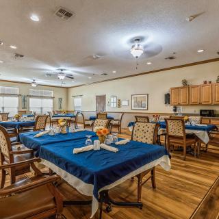 A spacious dining area with blue tablecloths and neatly arranged tables and chairs.