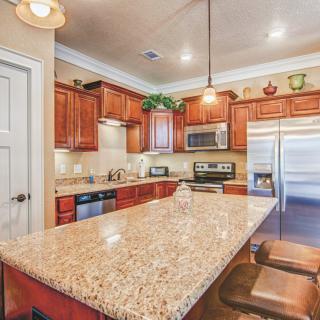 A modern kitchen with wooden cabinets, a granite countertop island, and sleek appliances.