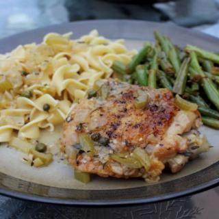 A plated meal featuring baked chicken, noodles, and green beans.