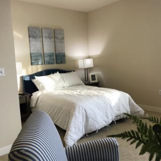 A cozy bedroom with a neatly made bed, bedside tables, lamps, and decorative artwork.