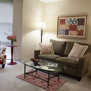 A cozy living room with a sofa, glass coffee table, and contemporary artwork.