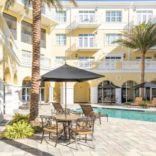 A serene outdoor pool area surrounded by palm trees and comfortable seating, perfect for relaxation.