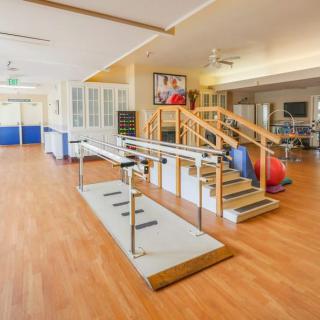 A spacious rehabilitation room equipped with physical therapy equipment.