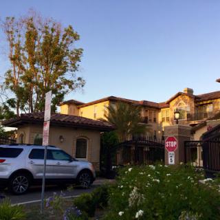 A serene view of a residential building with beautiful landscaping at sunset.