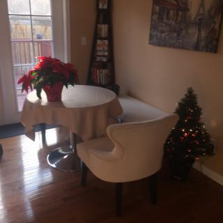 A cozy indoor corner with a table, chairs, poinsettia, and a small Christmas tree.