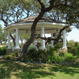A picturesque gazebo surrounded by trees in a garden setting.