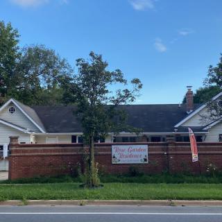 A house with a wooden fence and banners along a roadside.