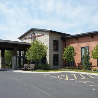A building entrance with a parking lot and surrounding trees.