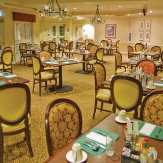 A formal dining room with neatly arranged tables and chairs, prepared for guests.