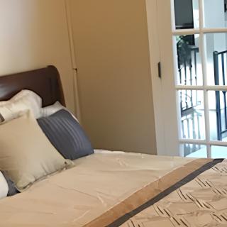 A cozy bedroom with a neatly made bed and accent pillows, featuring a sliding door.
