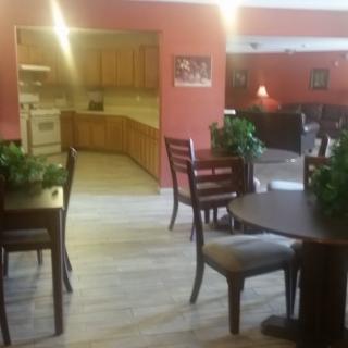 A cozy dining area with wooden tables and chairs, adjacent to a kitchen.