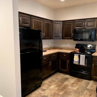 A modern kitchen featuring black appliances and dark wood cabinetry.