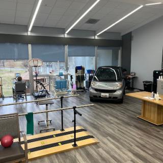 A well-equipped physical therapy room featuring various rehabilitation tools and a smart car.