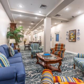 A spacious and elegantly decorated living room area featuring comfortable seating, a wooden coffee table, and vibrant artwork.