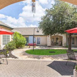 A sunny courtyard with outdoor seating and red umbrellas.