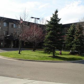 A building surrounded by trees and a circular road under a partly cloudy sky.