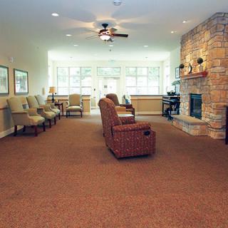 A spacious living room with comfortable seating and a cozy fireplace, illuminated by natural light.