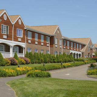 A well-maintained brick building with landscaped gardens and a pathway.