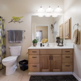 A modern bathroom with a wooden vanity, large mirror, and warm lighting.