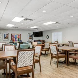 A well-lit dining area with multiple tables and chairs, complemented by artwork on the walls.