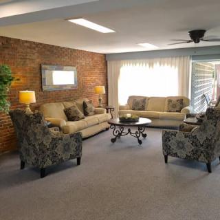 A cozy living room with sofas and armchairs arranged around a coffee table, accented by a brick wall.