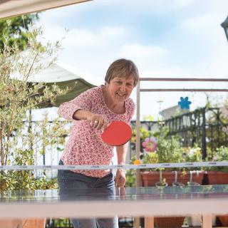 A woman playing table tennis outdoors.