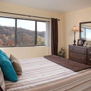 A cozy bedroom with a striped bedspread and a view of the outdoors.