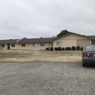 A gray day at a residential building with a parked car in front.