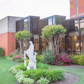 A beautifully landscaped garden with a statue in front of a modern building.
