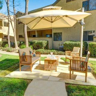 A cozy patio area with wooden furniture and a large umbrella in an apartment complex garden.