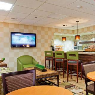 A cozy hotel lounge with comfortable seating, bar stools, and a mounted TV.