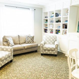 A cozy living room with a sofa, armchair, and built-in bookshelf under natural light.
