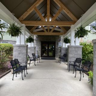 A covered entrance with outdoor seating and hanging plants.