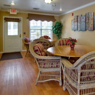 A cozy dining area featuring wicker chairs and a round wooden table, with warm lighting and decor.
