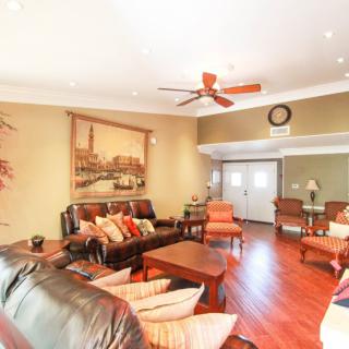 A cozy living room with comfortable seating, artwork on the wall, and a ceiling fan.