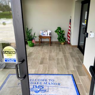 Entrance to an establishment featuring a welcome mat and decorative plants.